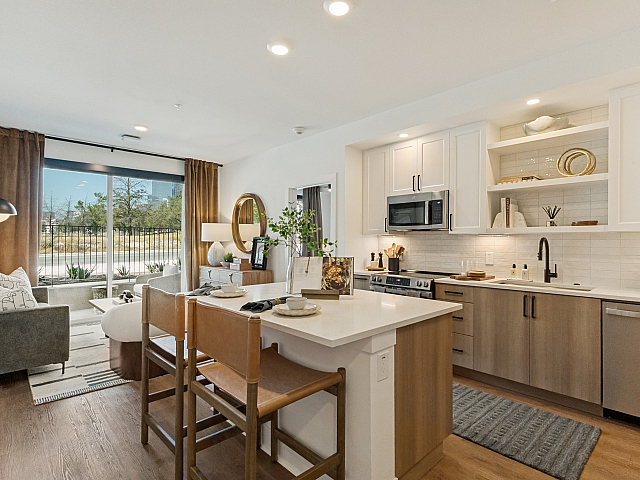 Modern open-concept apartment featuring a sleek kitchen with white cabinetry, a cozy living area with stylish decor, and large windows offering natural light.