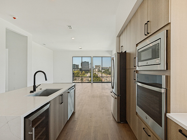Sleek modern kitchen with high-end appliances and expansive city views from floor-to-ceiling windows.