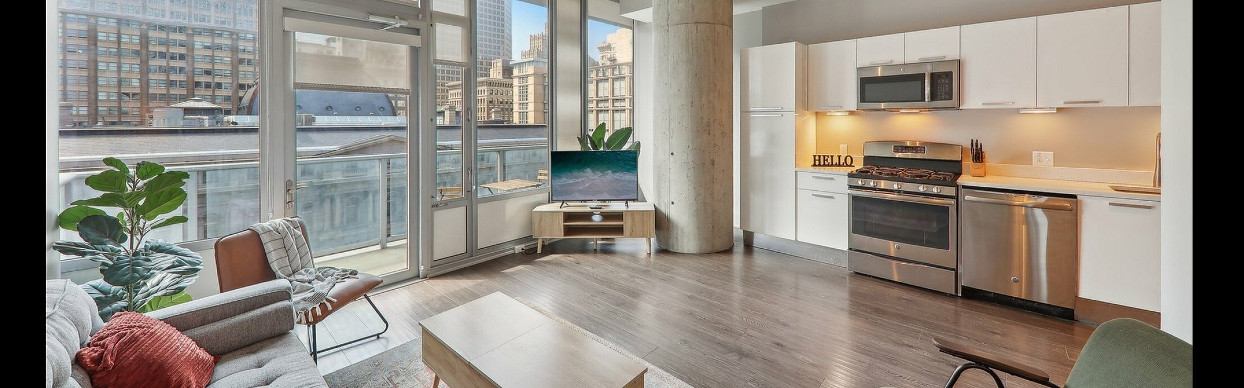 Modern open-concept apartment with floor-to-ceiling windows, stylish kitchen, and inviting living area with city view.