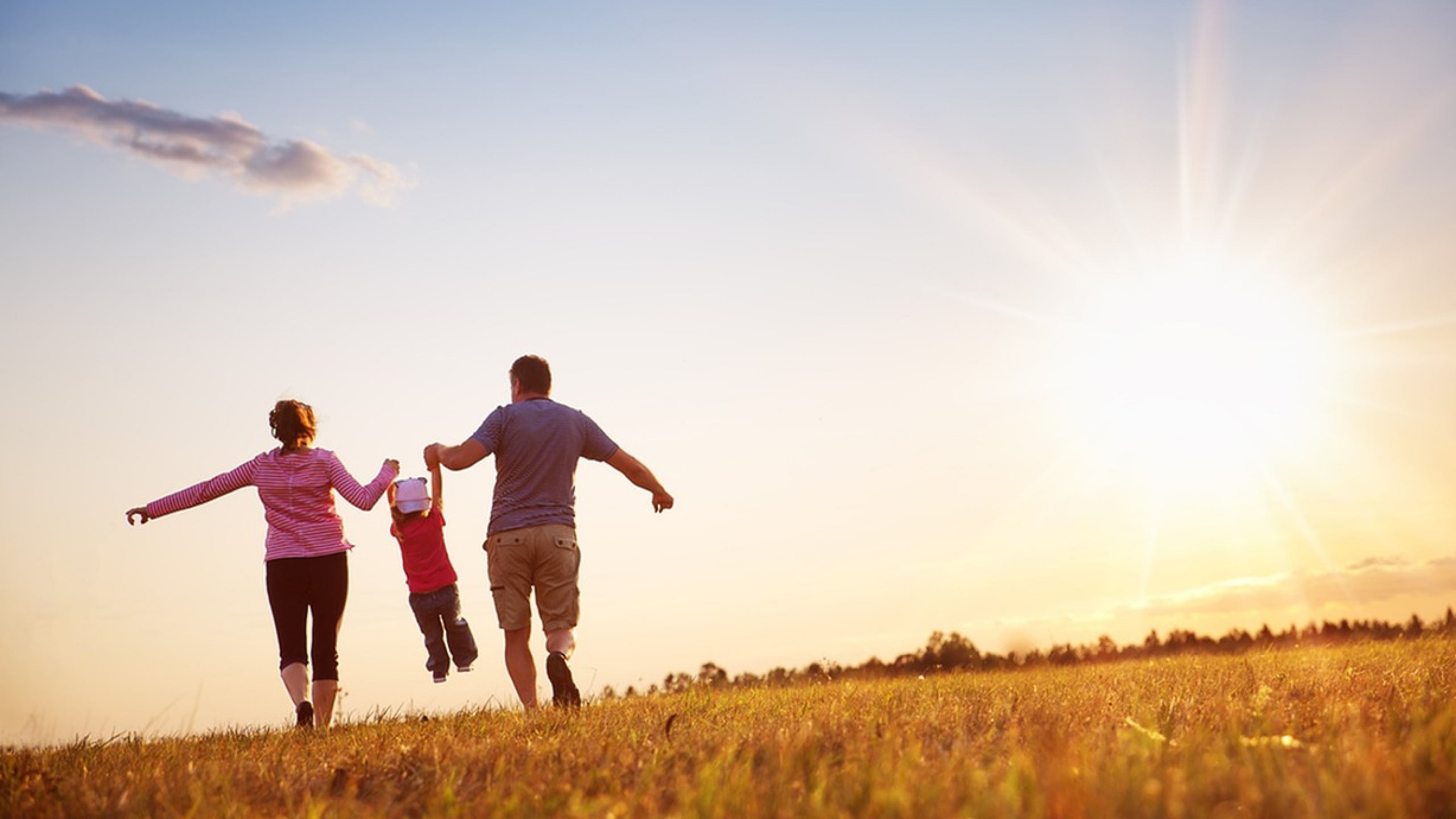 Joyful family playing in open field at sunset