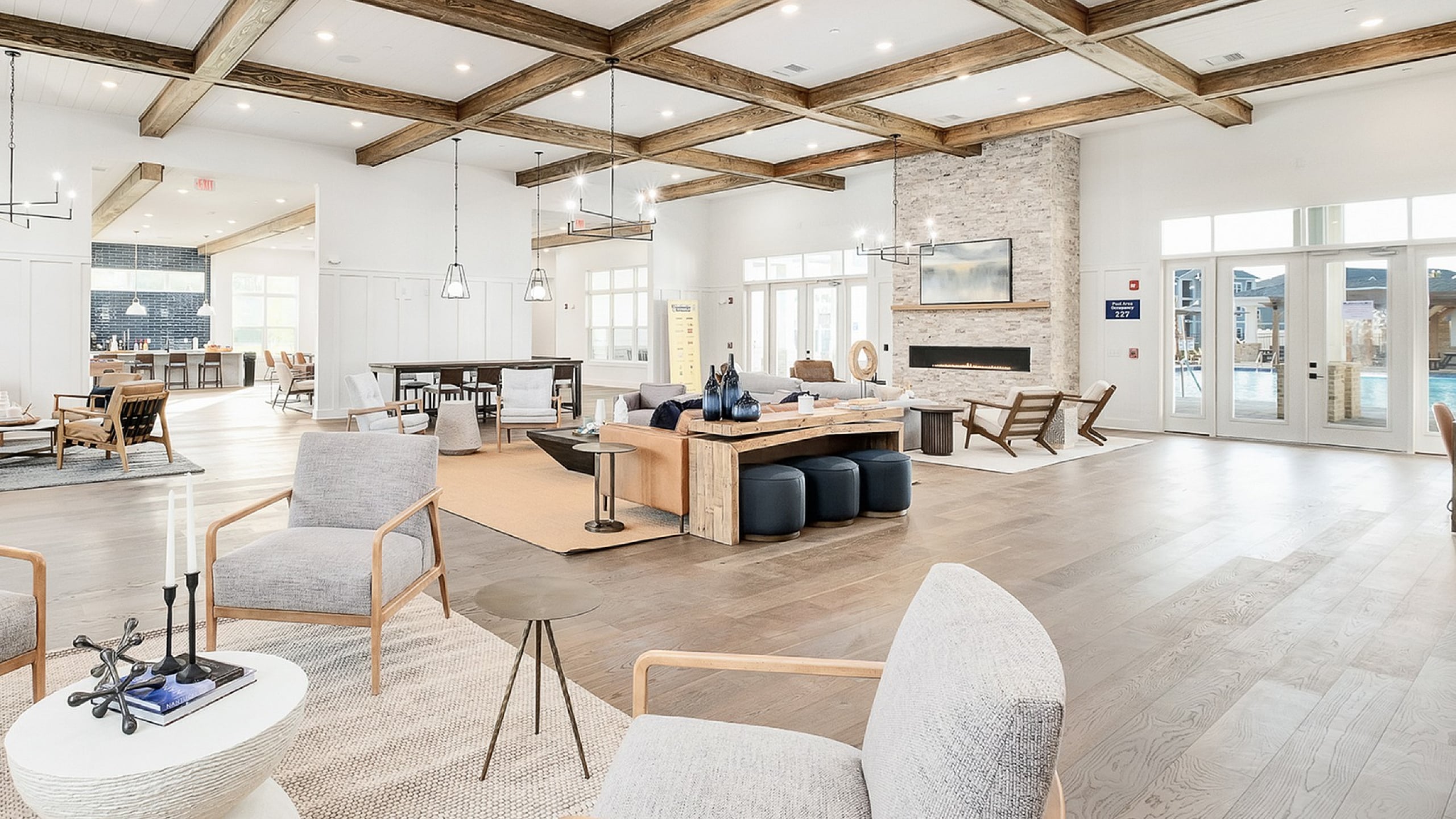 Luxurious open-concept living space featuring elegant wood-beam ceilings, cozy seating areas, and a modern stone fireplace for a welcoming atmosphere.
