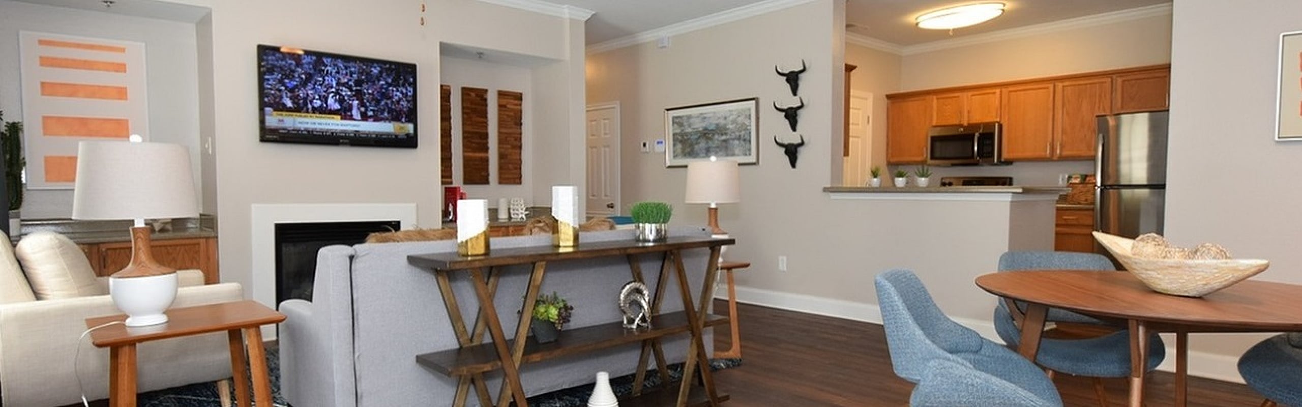 Inviting open-concept living room with wooden floors, modern kitchen, and stylish dining area under soft lighting.