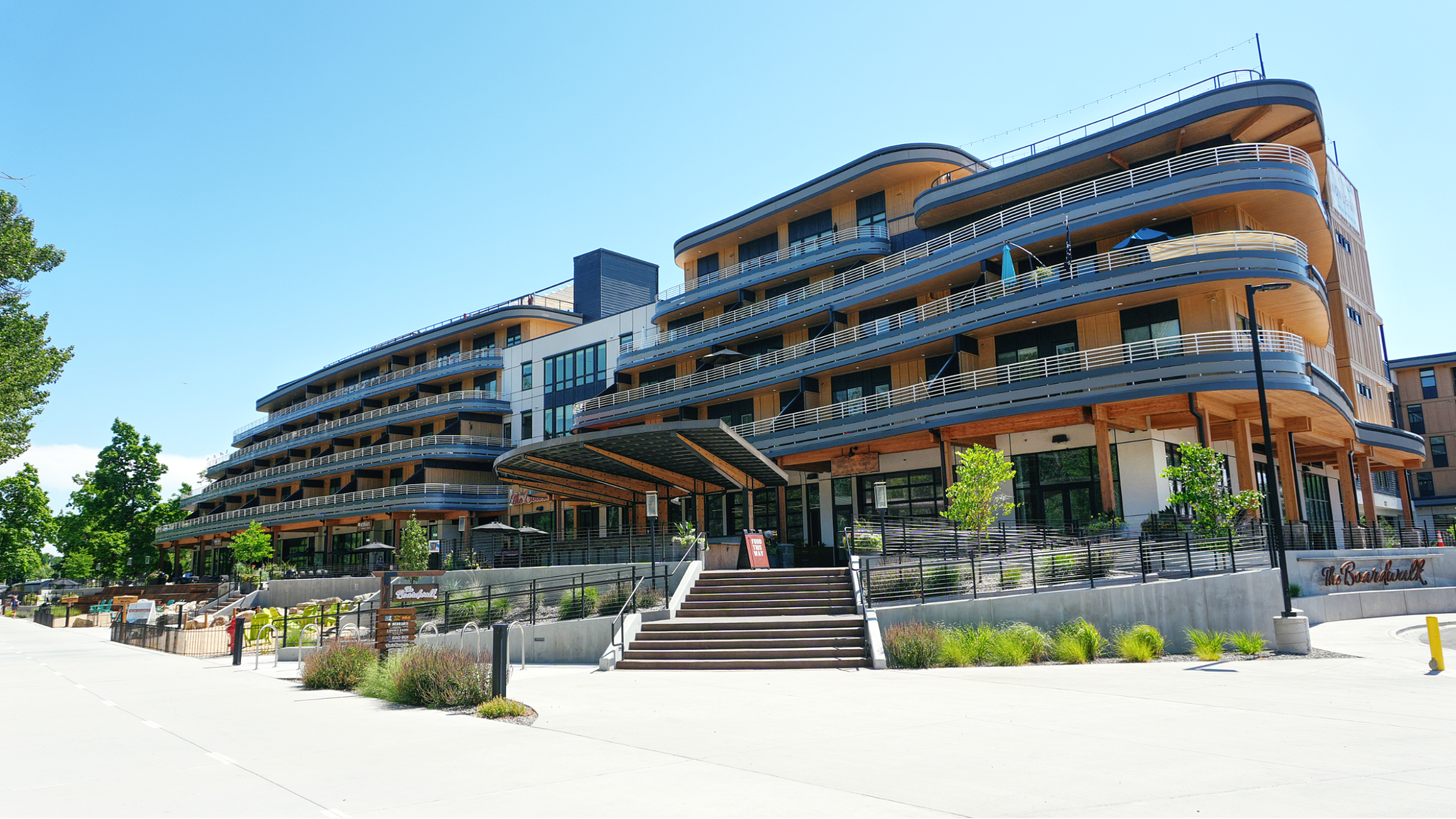 Modern apartment complex with sleek curved balconies and landscaped surroundings, showcasing a stylish and inviting architectural design.