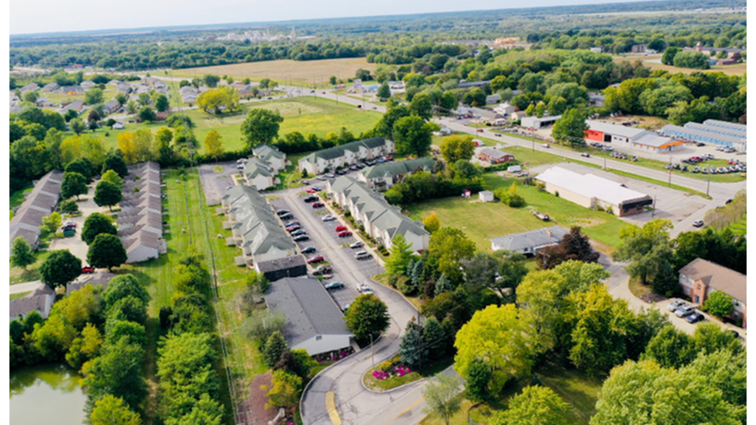 Charming aerial view of a serene residential community surrounded by lush greenery, offering peaceful living with convenient nearby amenities.