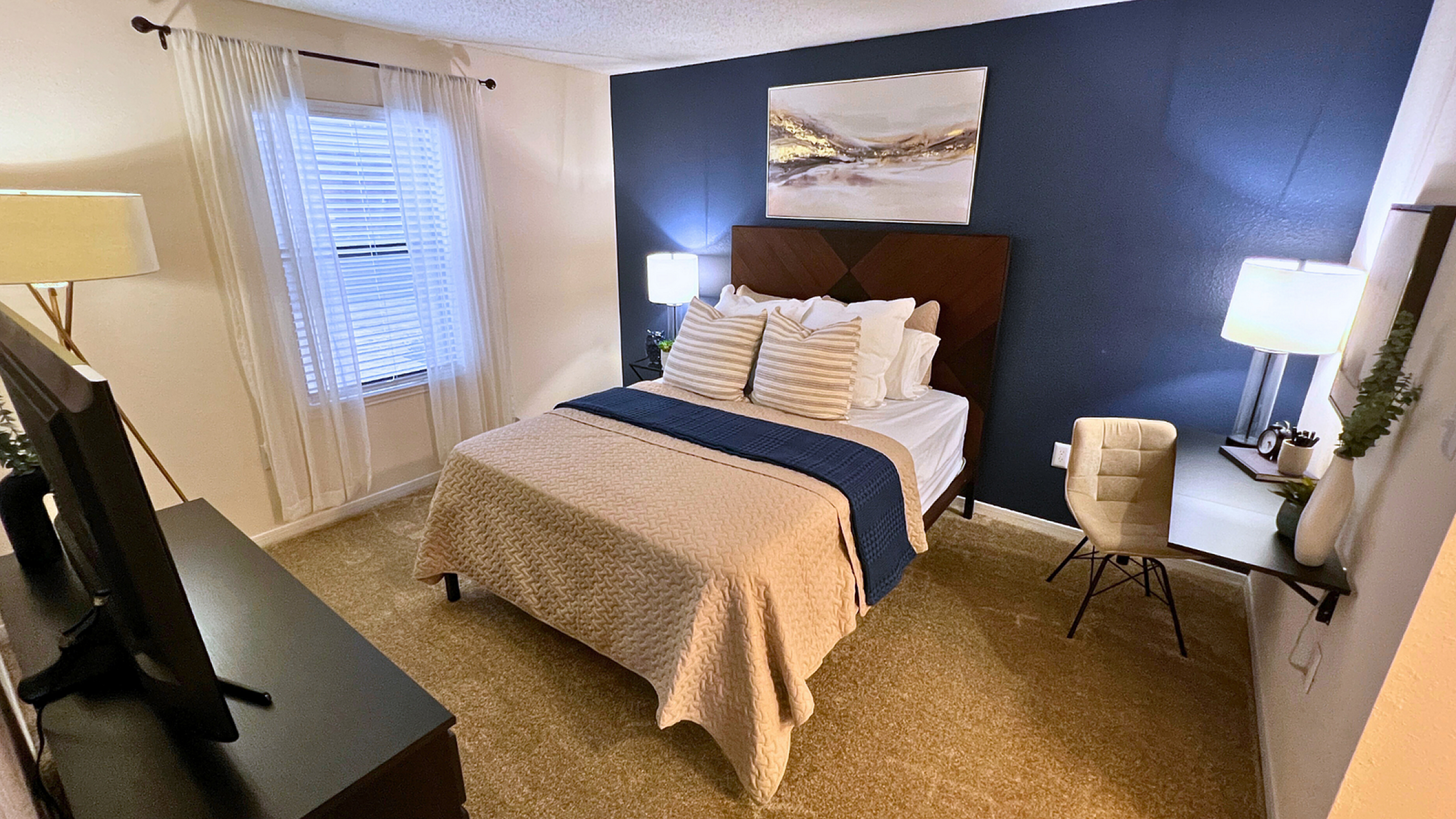 Inviting bedroom featuring a cozy bed with elegant headboard, stylish decor, and a dedicated workspace, ideal for comfort and relaxation.