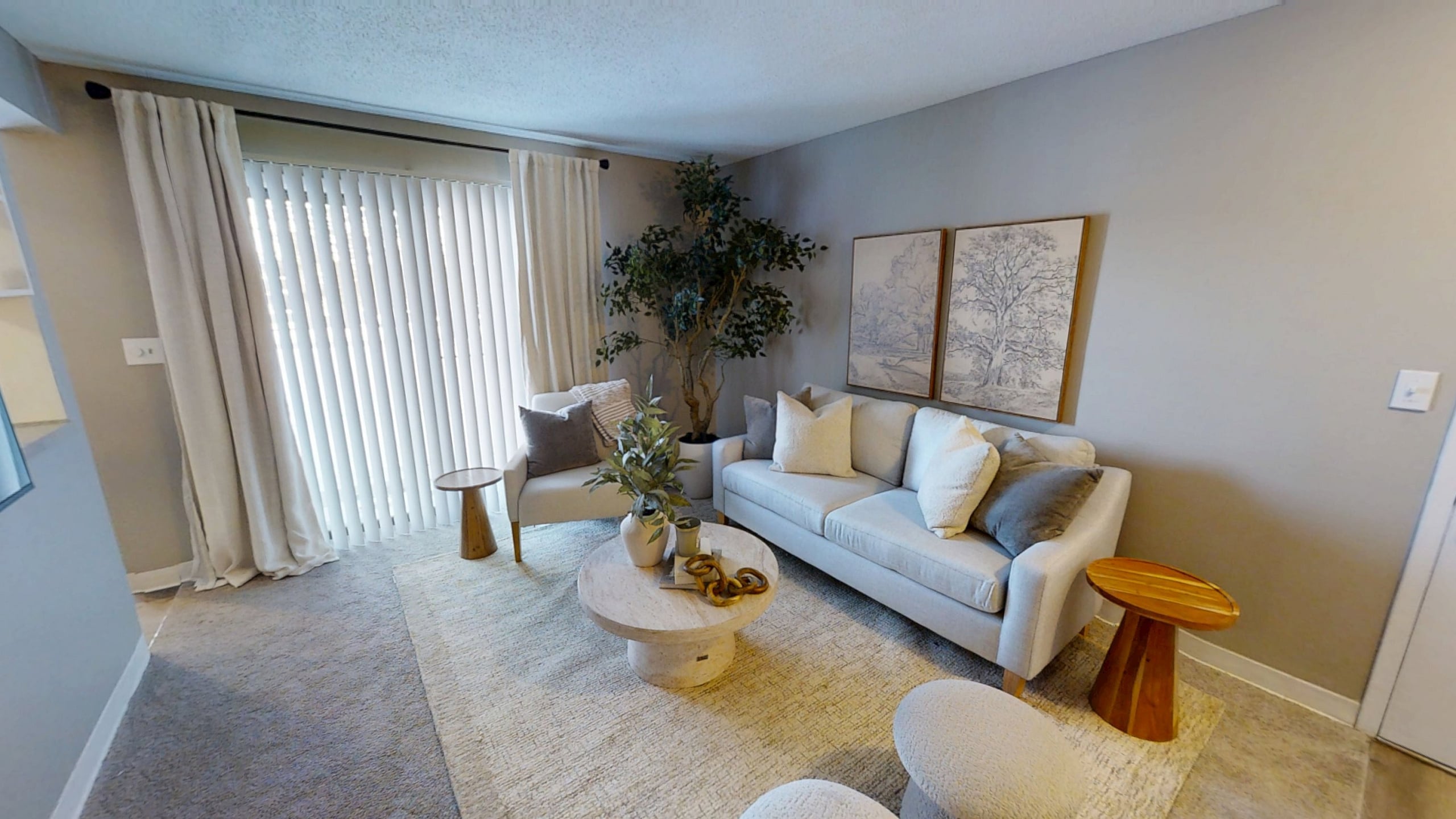 Pebble Point chic living room with elegant neutral tones, featuring a plush sofa, cozy armchair, and stylish decor, complemented by natural light from large vertical blinds.