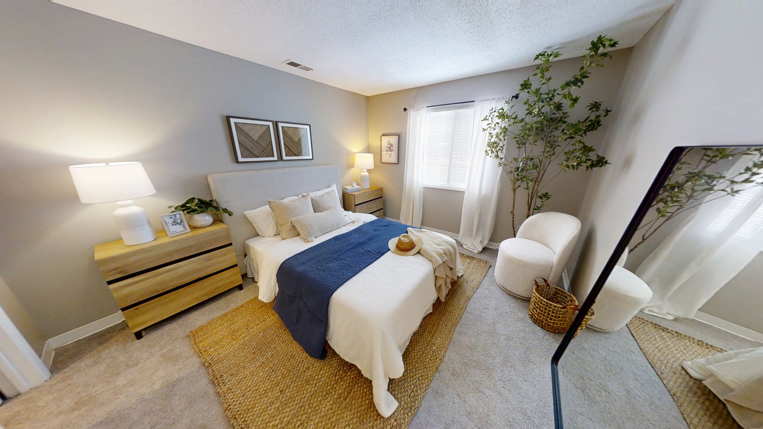 Pebble Point inviting bedroom with soft hues, featuring a plush bed with a navy throw, stylish wooden side tables, and serene natural lighting.