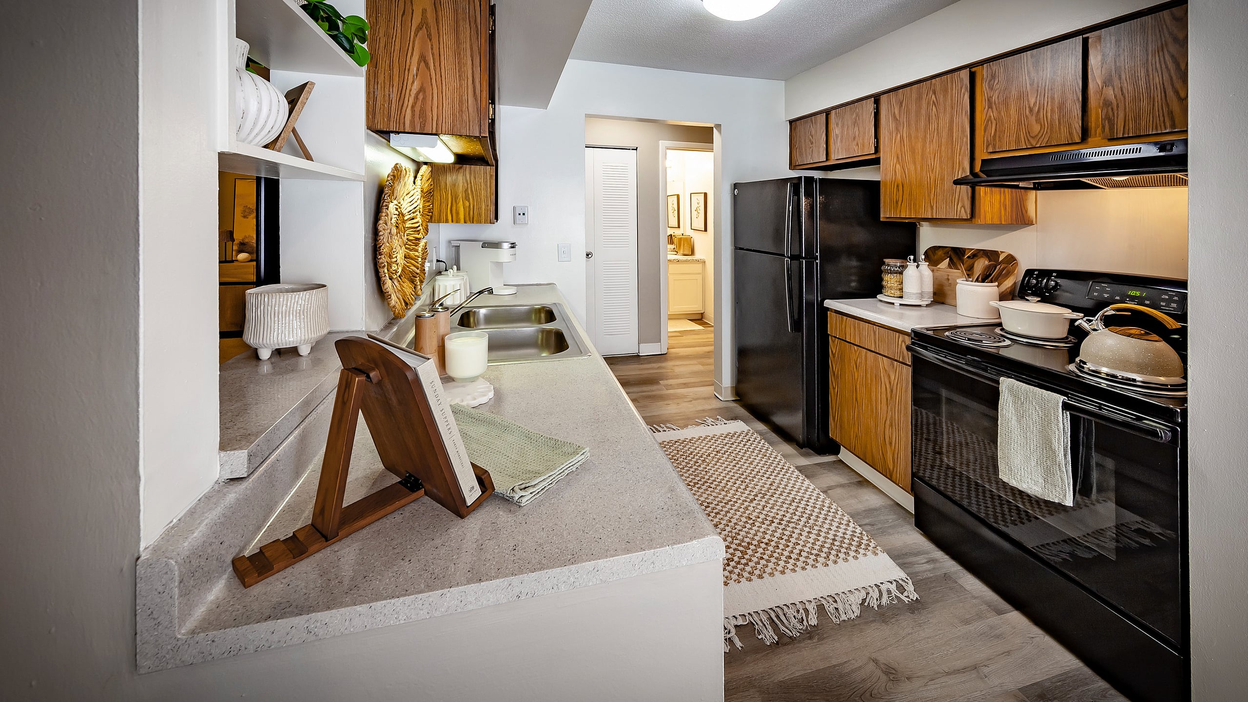 Charming kitchen with sleek countertops, wooden cabinetry, and modern appliances, accented by a cozy rug and decorative accents.