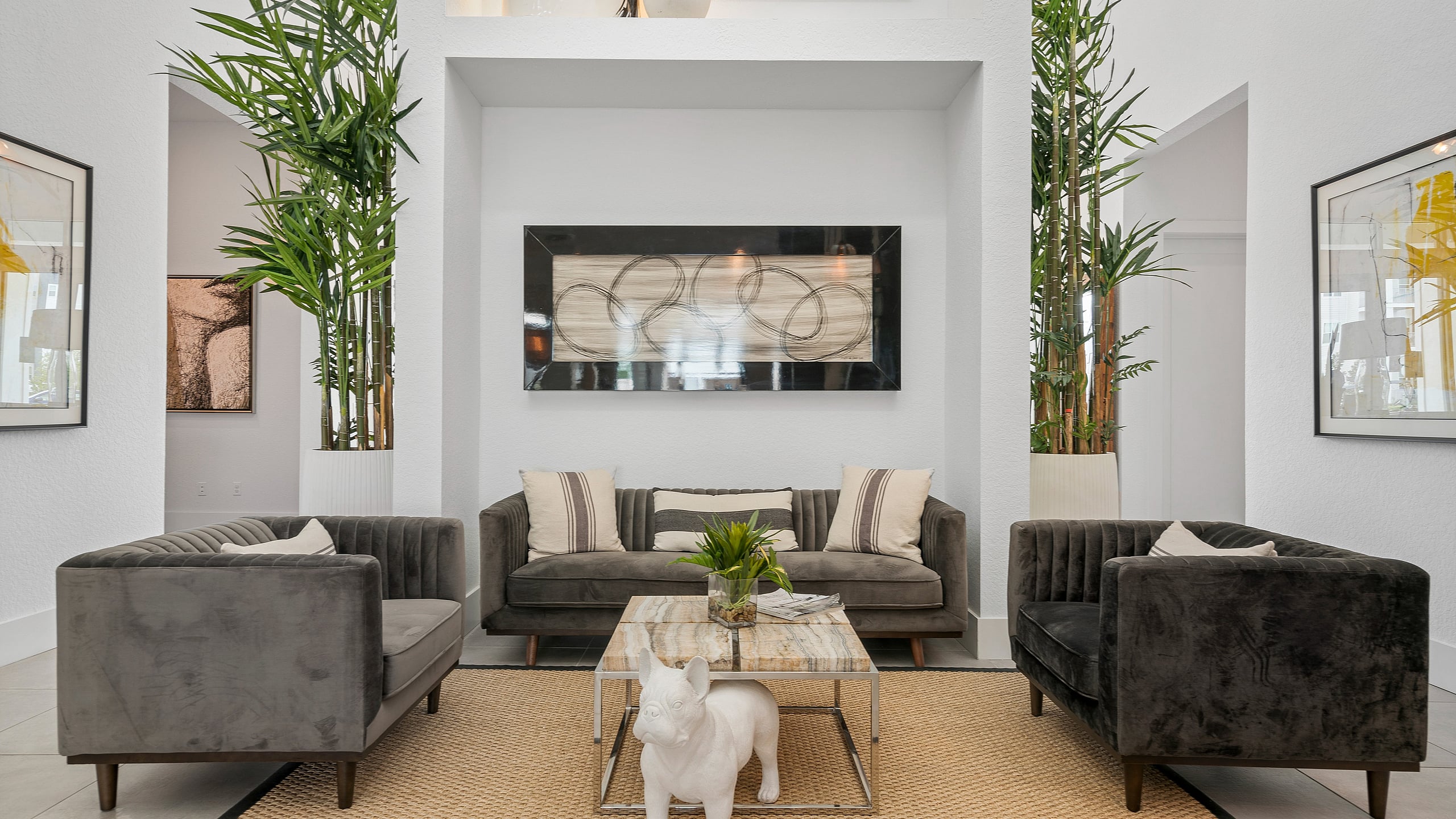 Luxurious modern living room with elegant grey sofas, stylish decor, and lush green plants creating a serene atmosphere.