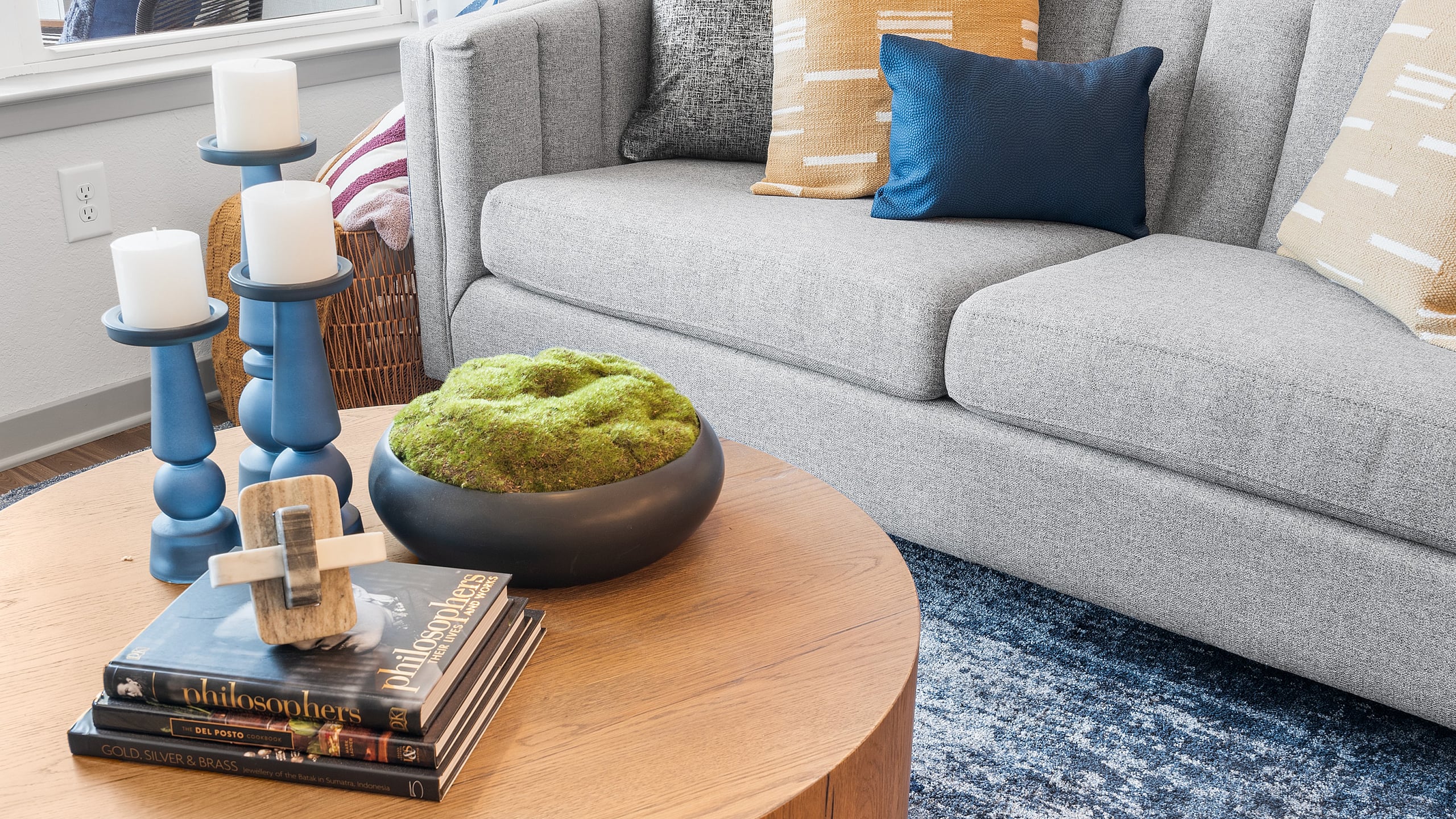 Chic living room with a stylish gray sofa, vibrant cushions, and a modern round coffee table adorned with elegant decor.