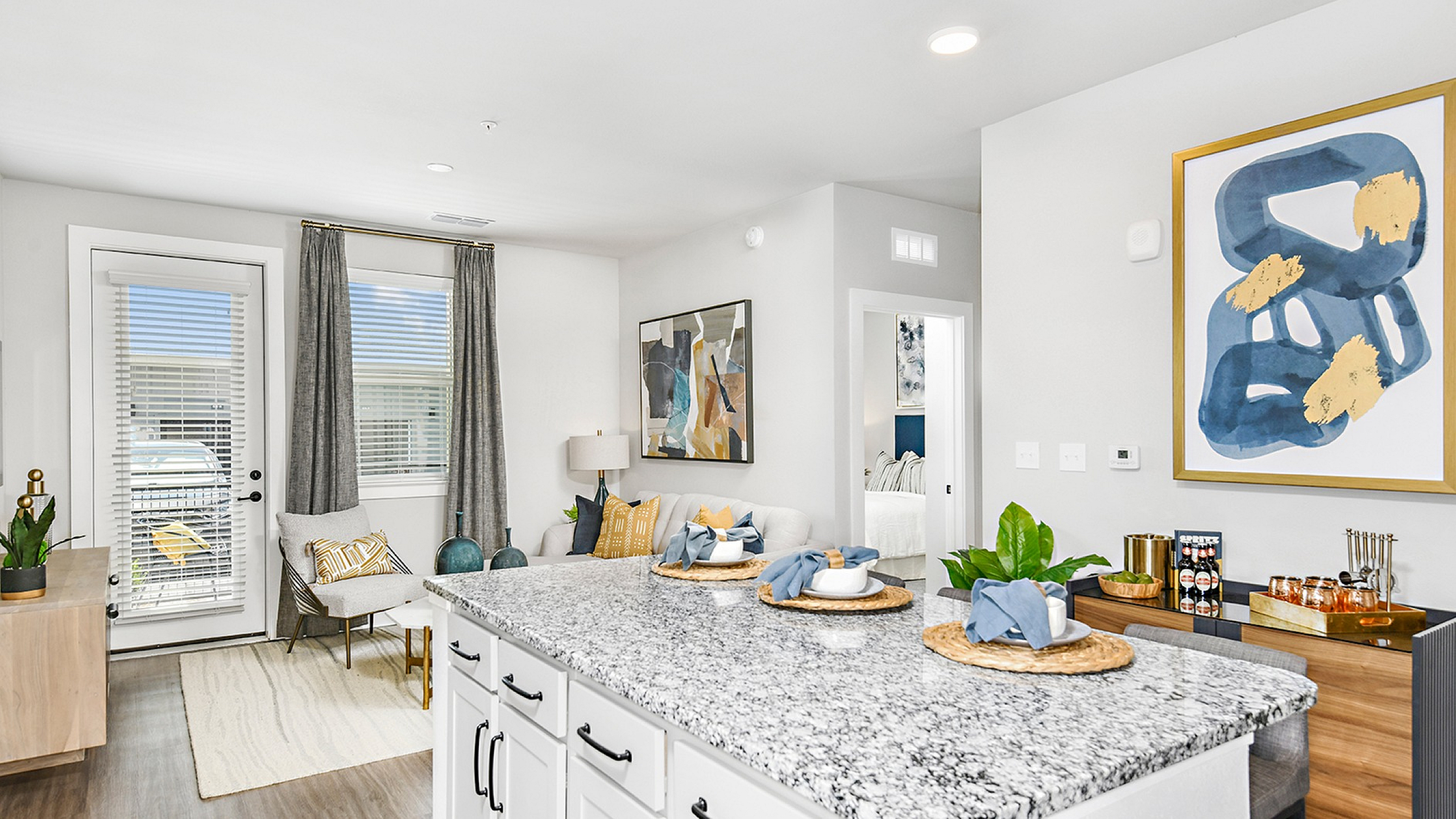 Bright modern living area featuring elegant granite kitchen island, stylish decor, and a cozy sitting space with contemporary artwork.