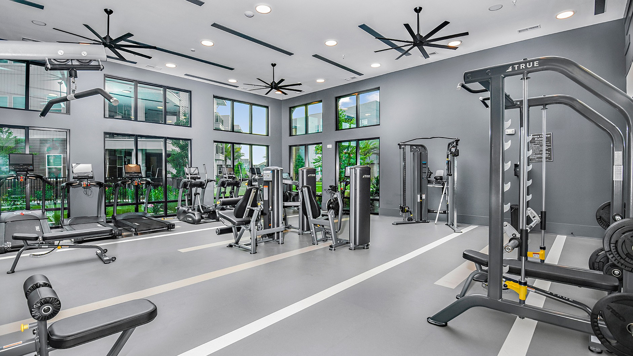 Spacious and modern fitness center with high ceilings, state-of-the-art equipment, and large windows offering scenic views.