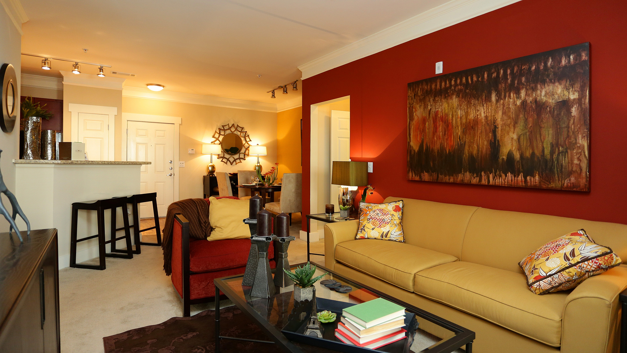 Inviting living room showcasing vibrant red and beige decor, modern art, and comfortable seating for a cozy atmosphere.