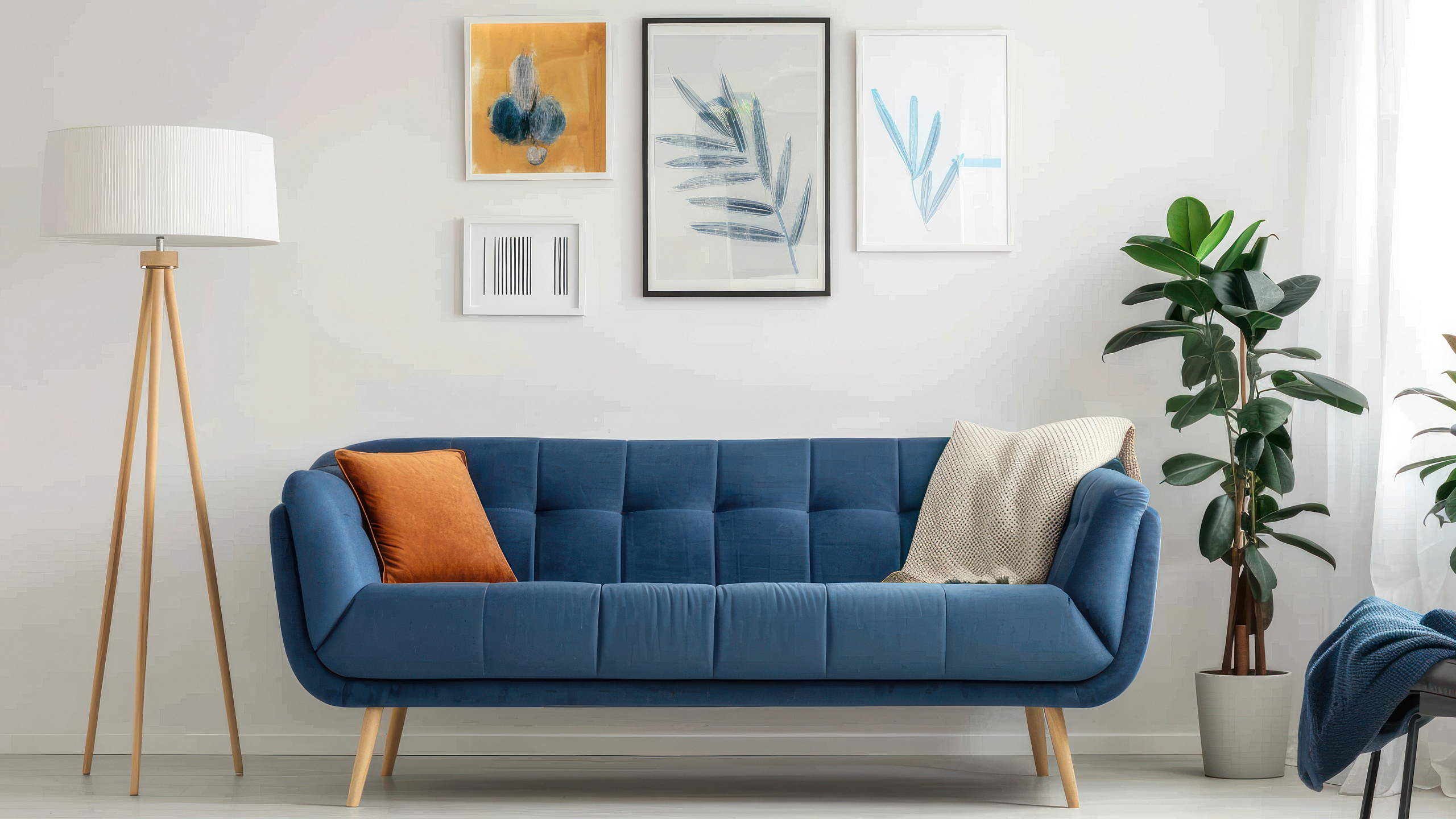 Contemporary living room with a stylish blue sofa, vibrant artwork, and lush green plants, creating an inviting and modern atmosphere.