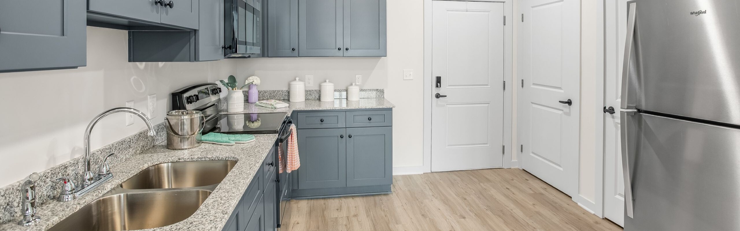 Modern kitchen with sleek stainless steel appliances, elegant blue cabinetry, and granite countertops, creating a stylish and functional cooking space.