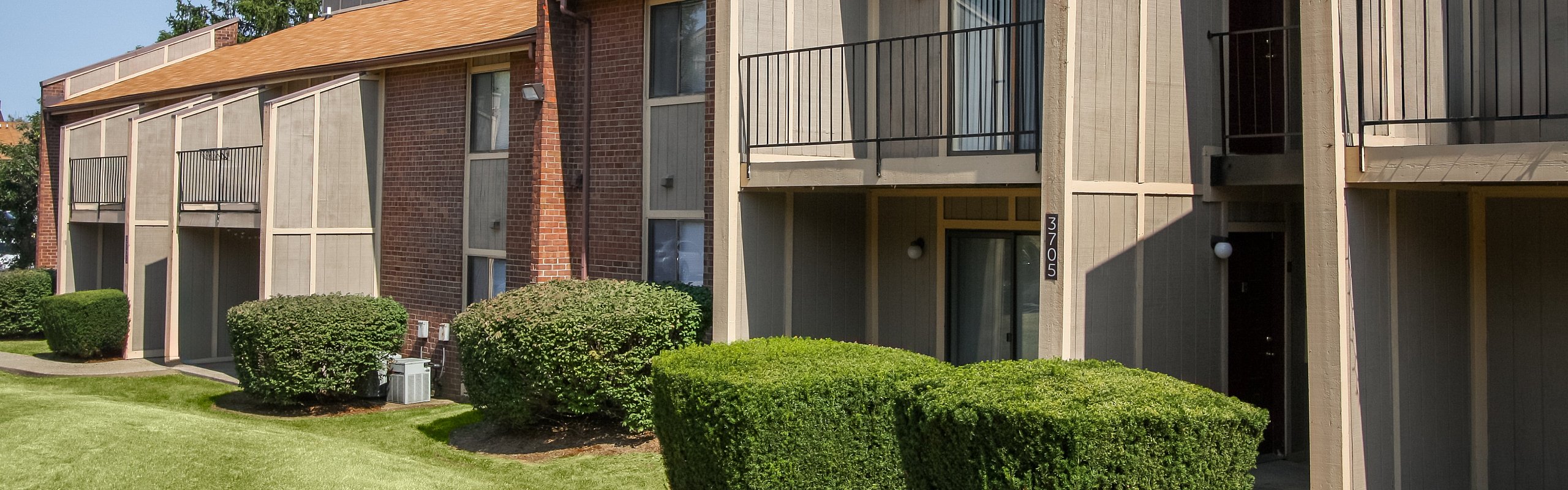 Charming apartment complex exterior featuring modern design, lush green lawns, and inviting balconies.