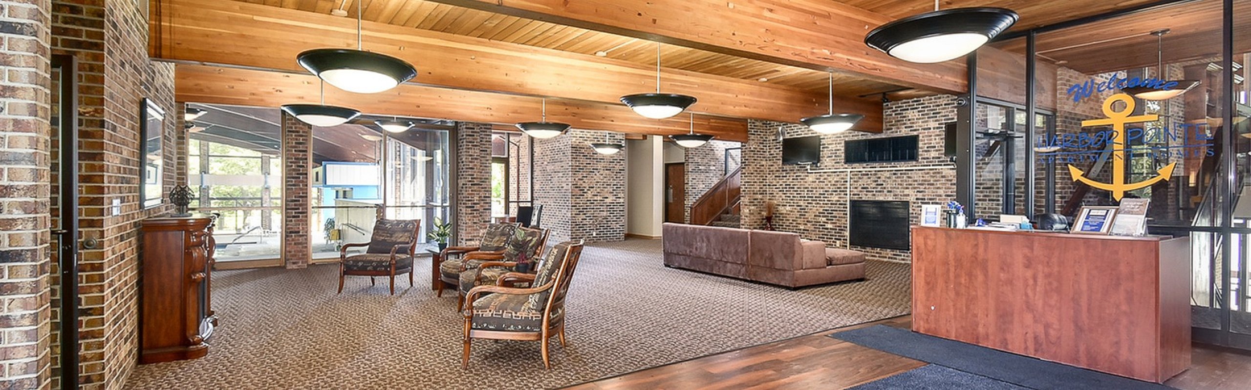 Inviting apartment lobby with warm wood ceilings, cozy seating areas, and charming brick accents.