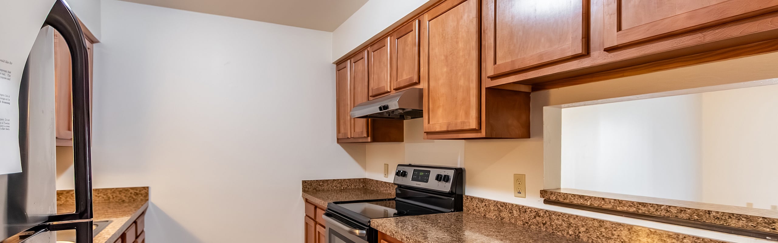 Elegant kitchen featuring modern appliances, granite countertops, and rich wood cabinetry creating a warm, inviting atmosphere.