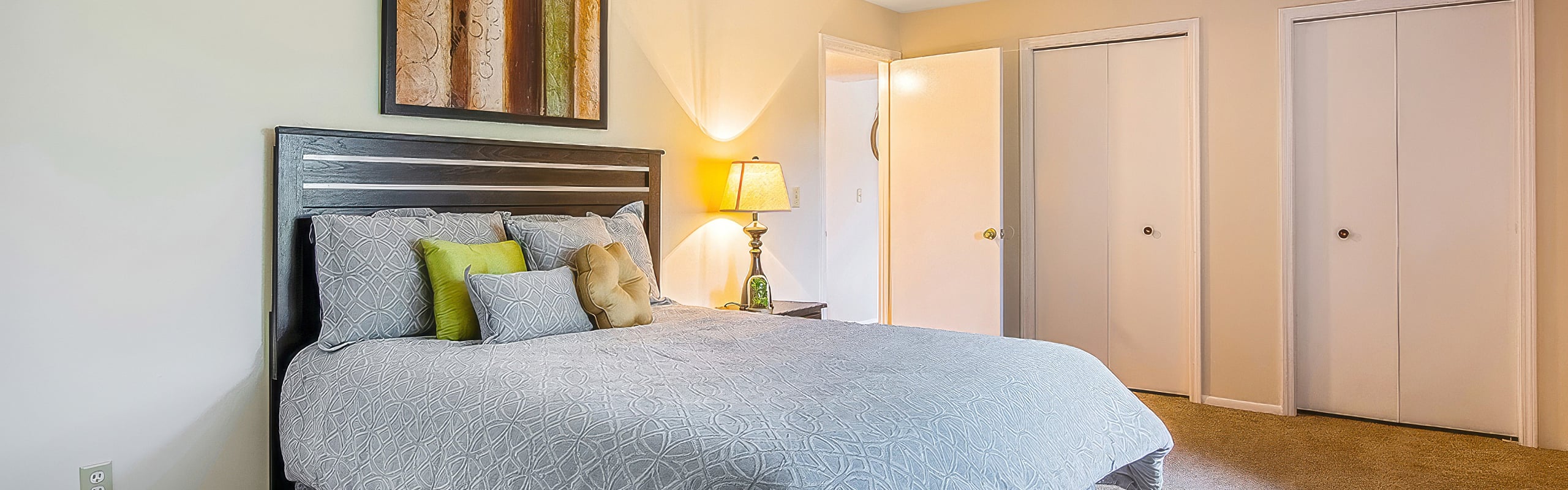 Cozy bedroom with elegant decor, featuring a plush bed, decorative pillows, warm lighting, and a stylish wall art piece.