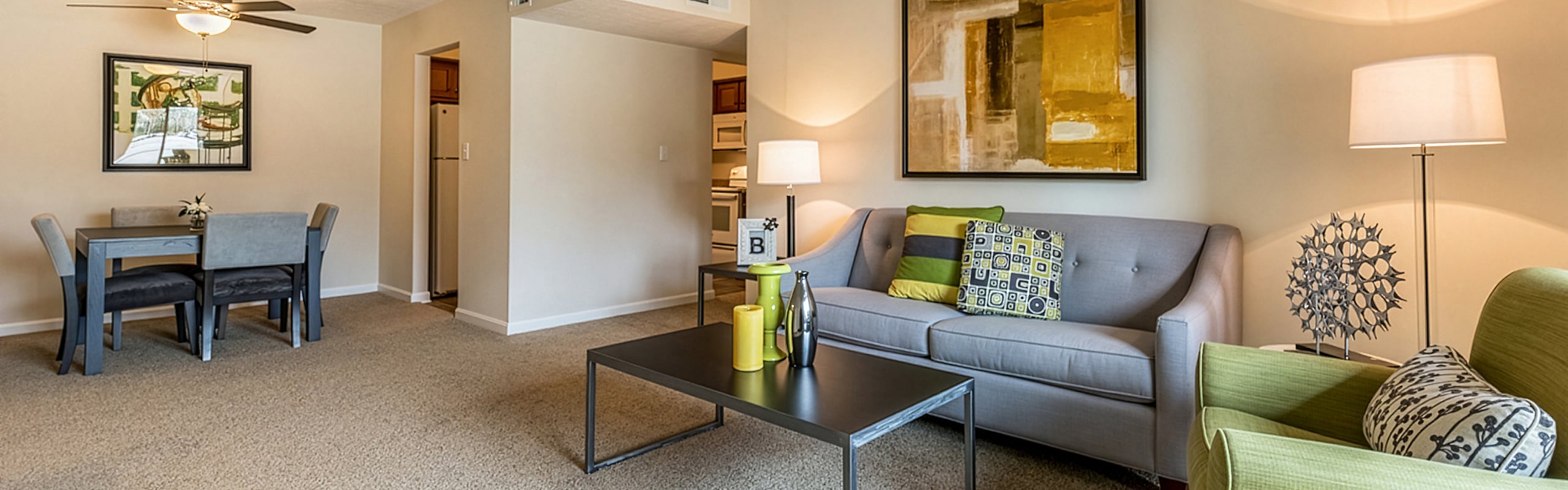 Inviting living room with elegant d&eacute;cor, cozy gray sofa, modern art pieces, and open dining area, creating a warm and stylish apartment ambiance.