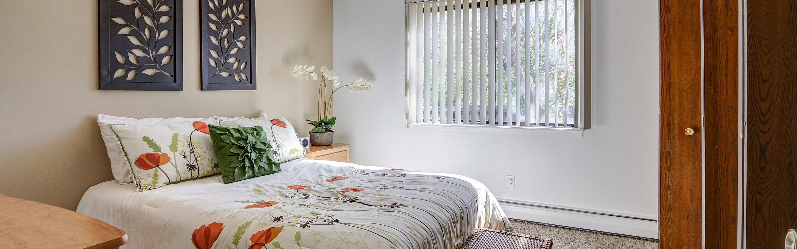 Bright, cozy bedroom showcasing a floral theme with a large window and elegant wall decor.