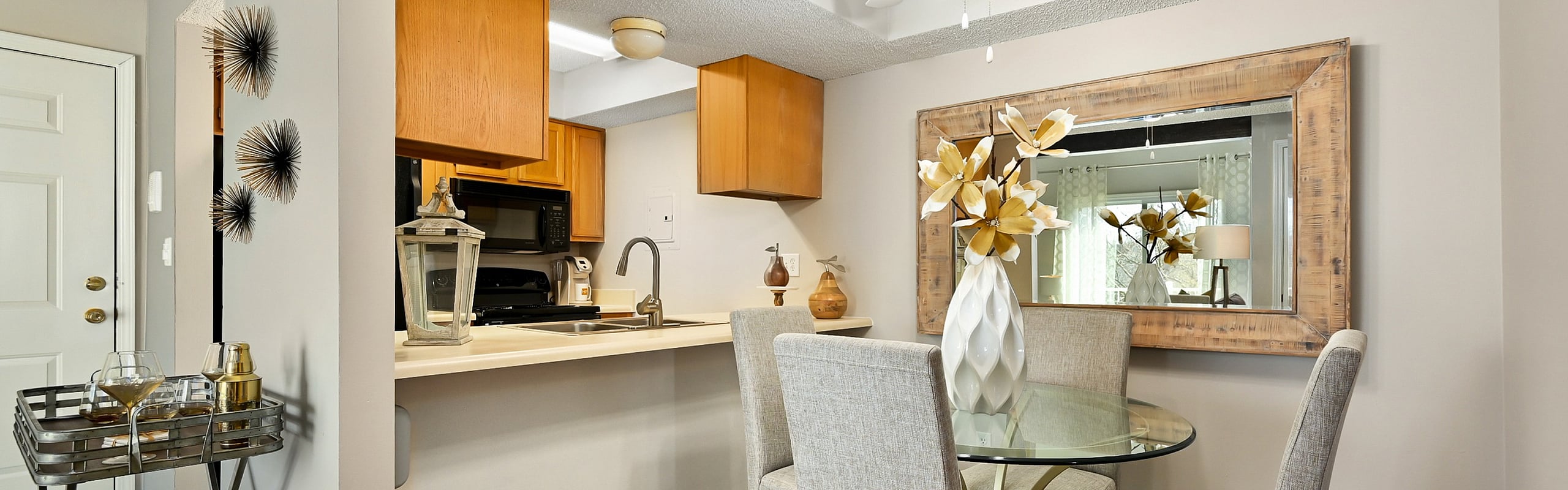 Charming kitchen and dining area with modern decor featuring a glass table, elegant vase arrangement, and warm wood cabinetry.