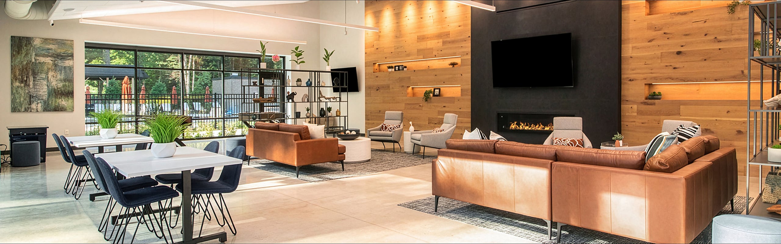 Modern communal lounge featuring stylish leather sofas, wall-mounted TV, and chic wooden accents under warm ambient lighting.