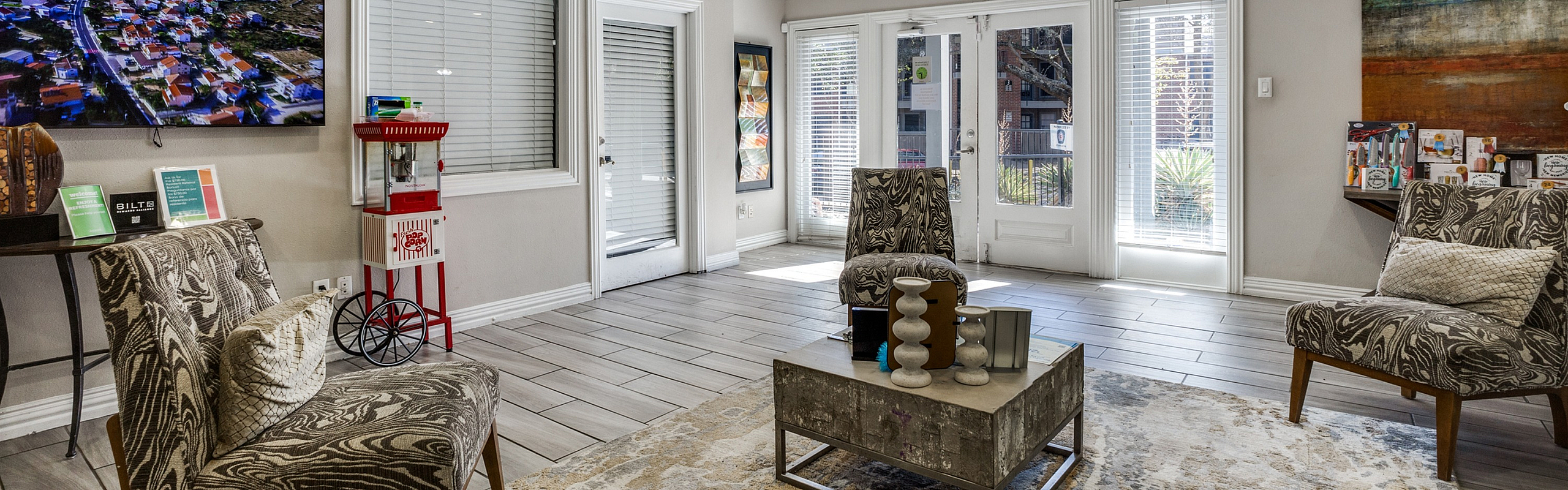 Inviting living area with modern decor, stylish seating, a popcorn machine, and large windows showcasing natural light.