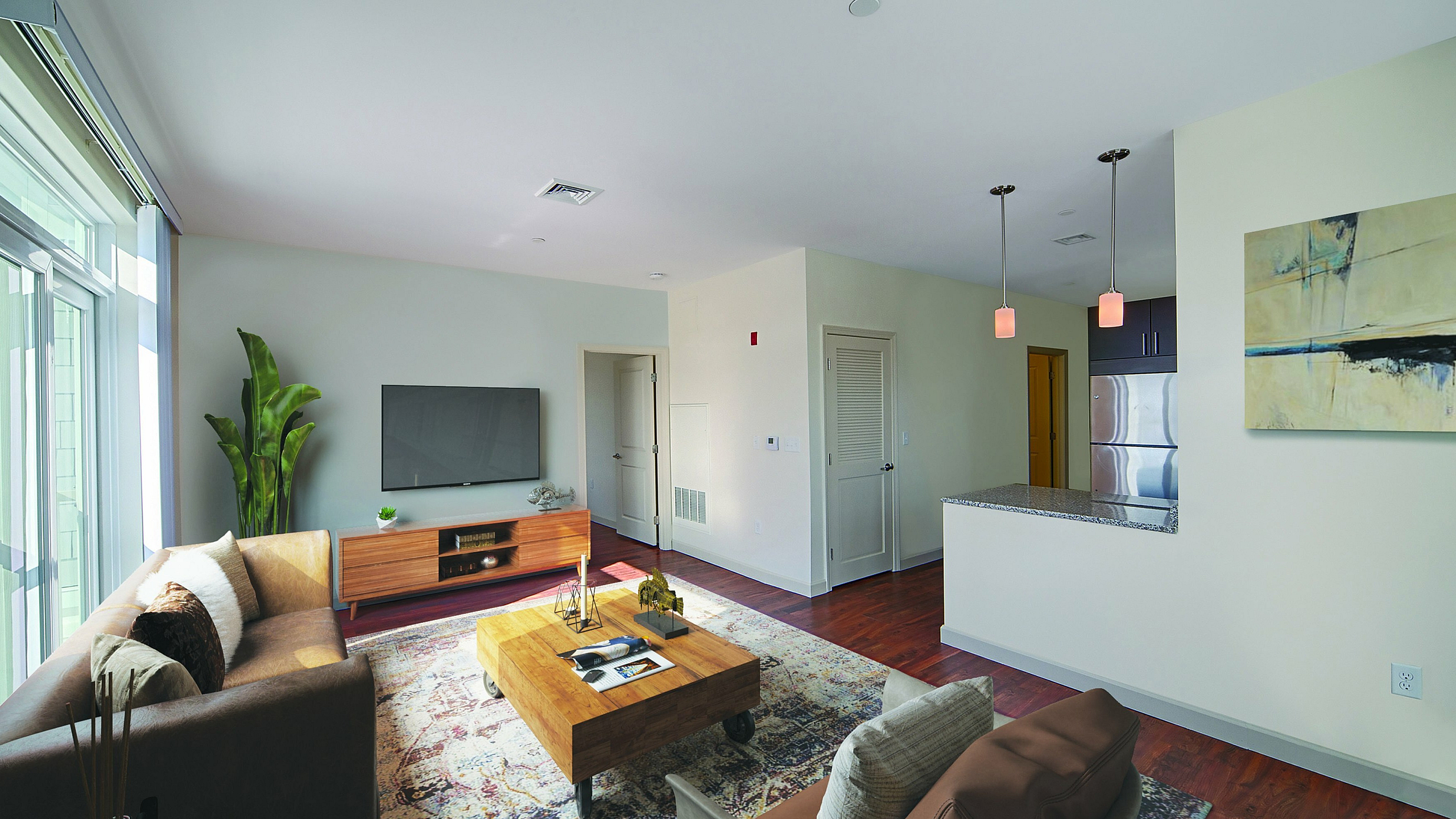 Chic and inviting living room with modern decor, large windows for natural light, and open kitchen with sleek countertops.