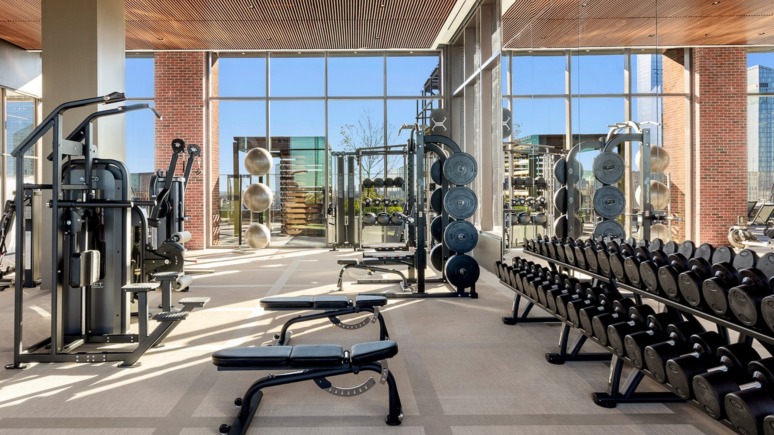 Modern fitness center boasting large windows, state-of-the-art equipment, and a well-lit gym environment.