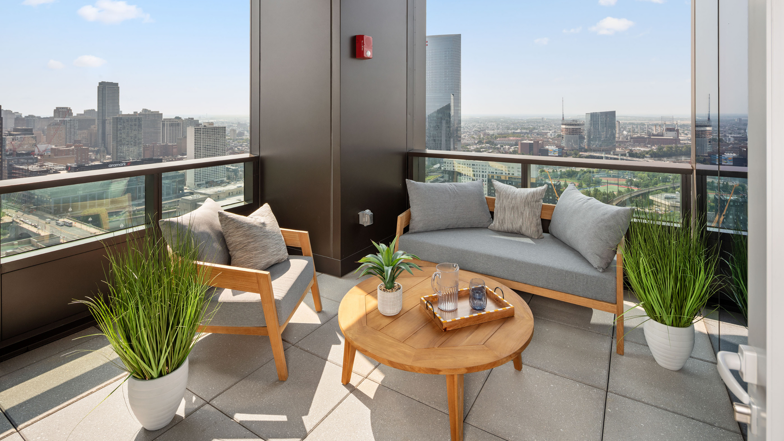 Luxurious high-rise balcony with cozy seating and panoramic city views, perfect for relaxing and entertaining.