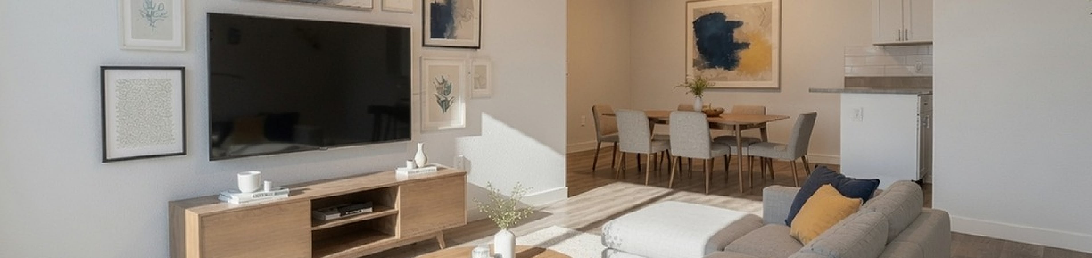 Modern living room with elegant decor, featuring a cozy sofa, stylish artwork, and a sleek wooden table bathed in natural light.