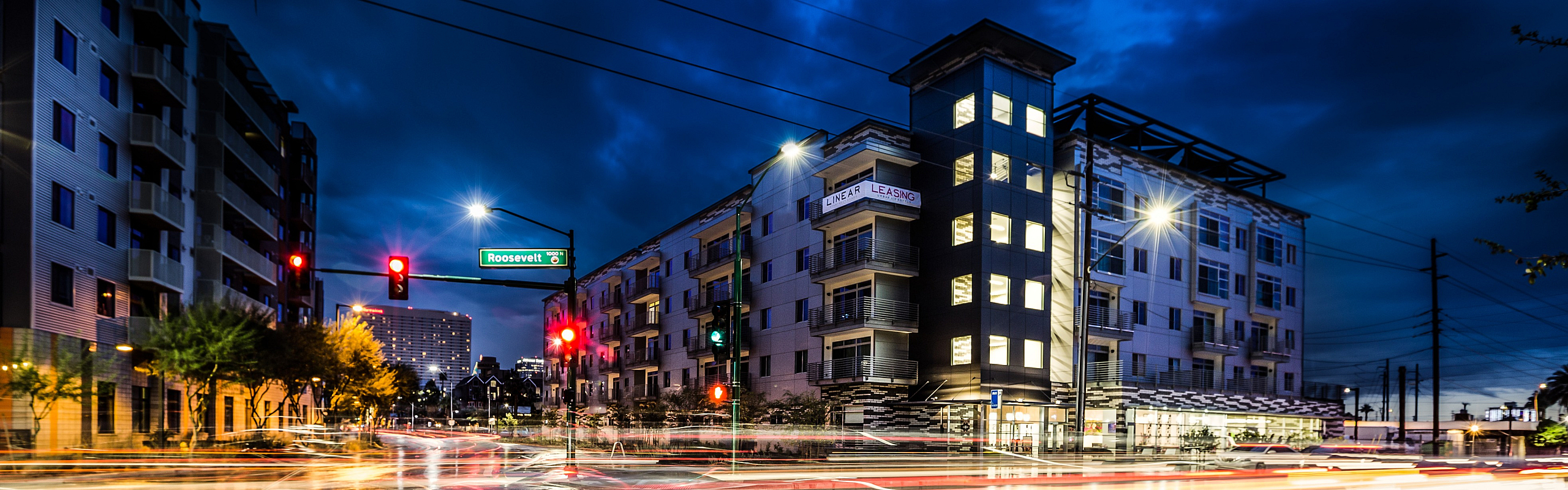 Dynamic urban living at night with modern apartment complex beautifully illuminated, framed by vibrant city lights and sleek architecture.