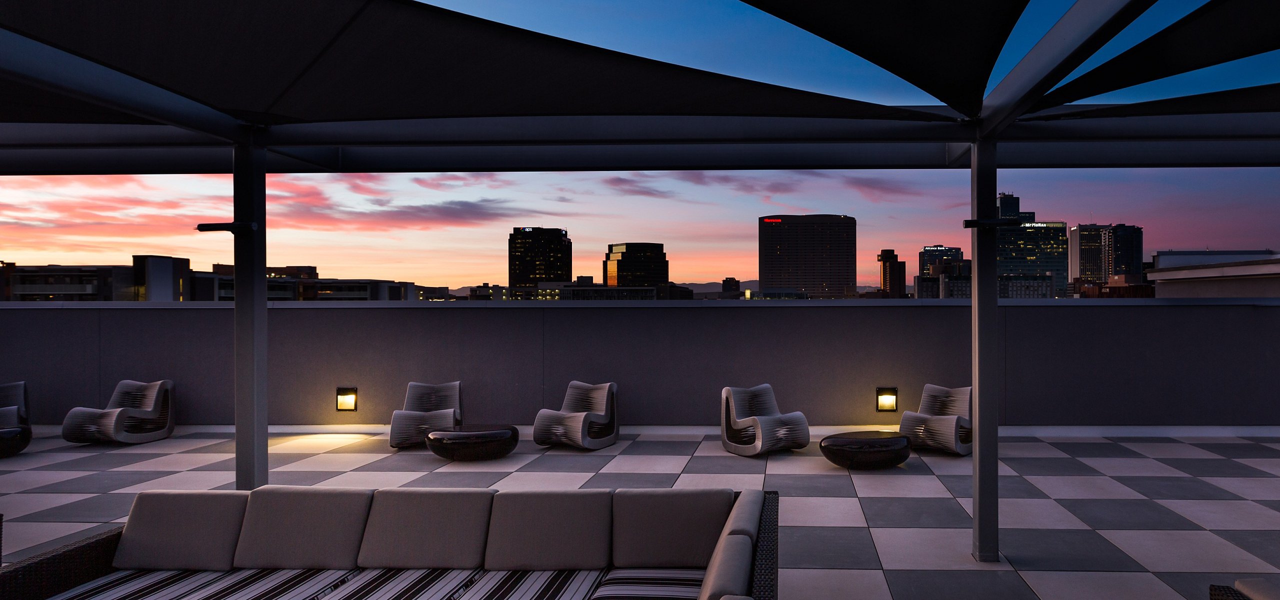 Luxurious rooftop terrace with modern seating, offering stunning cityscape views at sunset.