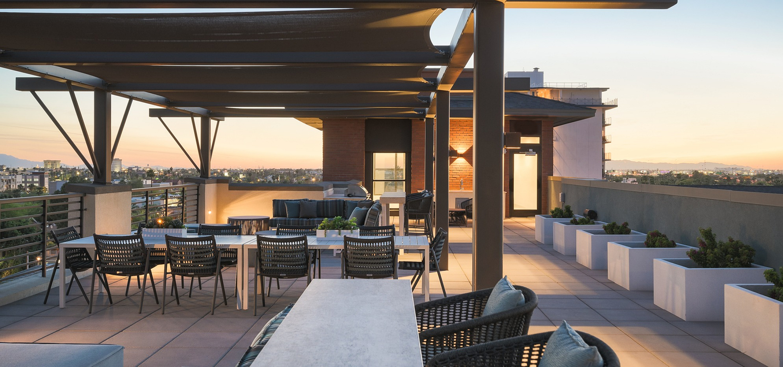 Stunning rooftop terrace with modern seating and panoramic city views at sunset.