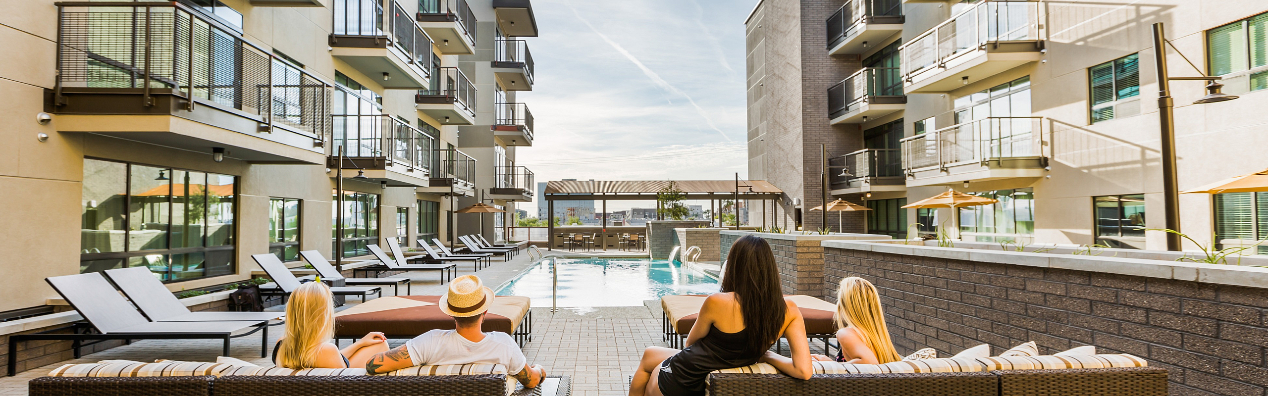 Luxurious apartment complex courtyard featuring a modern pool surrounded by stylish lounging areas and lush landscaping, creating a perfect oasis for relaxation.