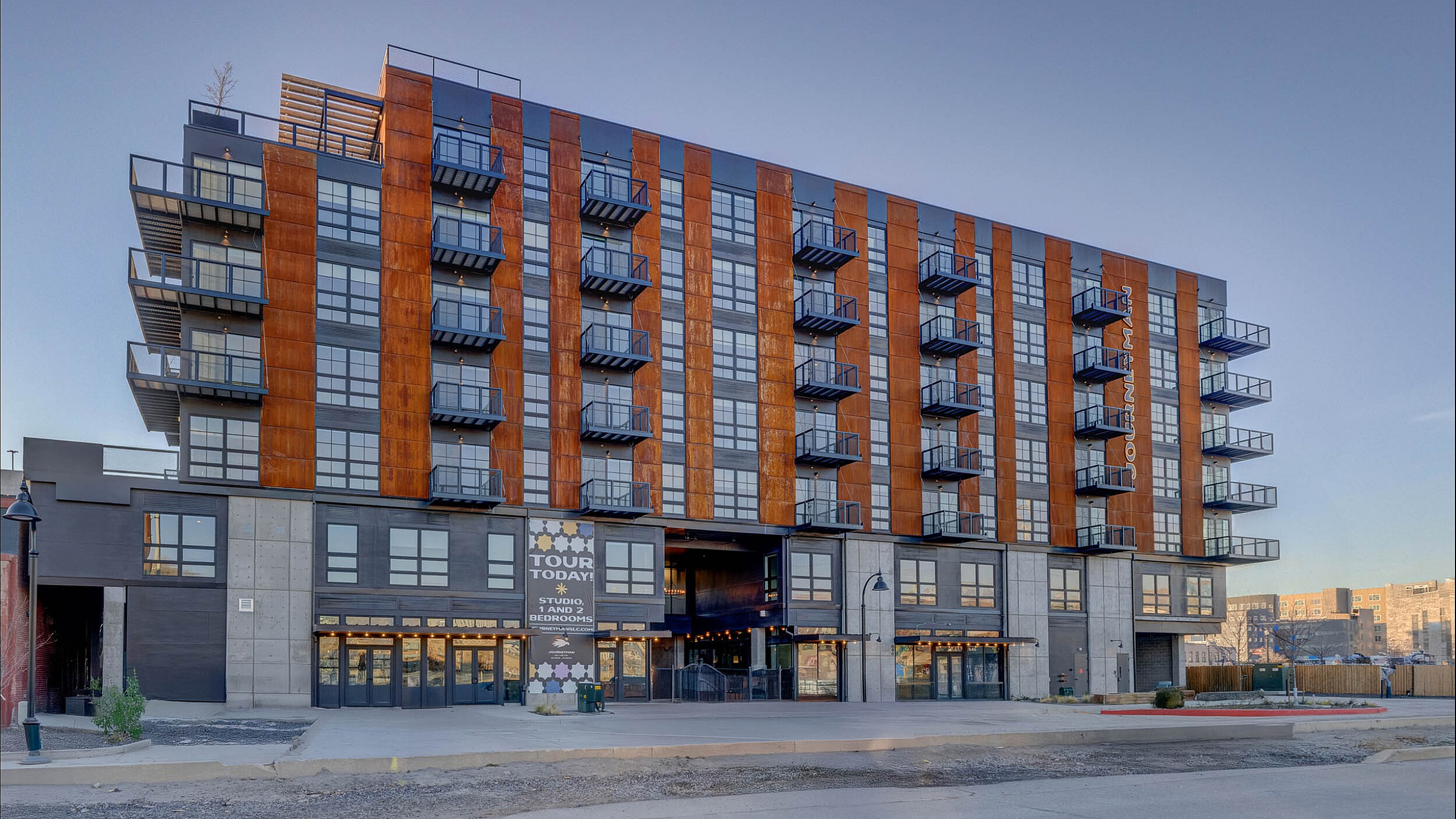 Modern apartment building featuring stylish balconies and contemporary design, offering studio, 1, and 2 bedroom units with inviting curb appeal.