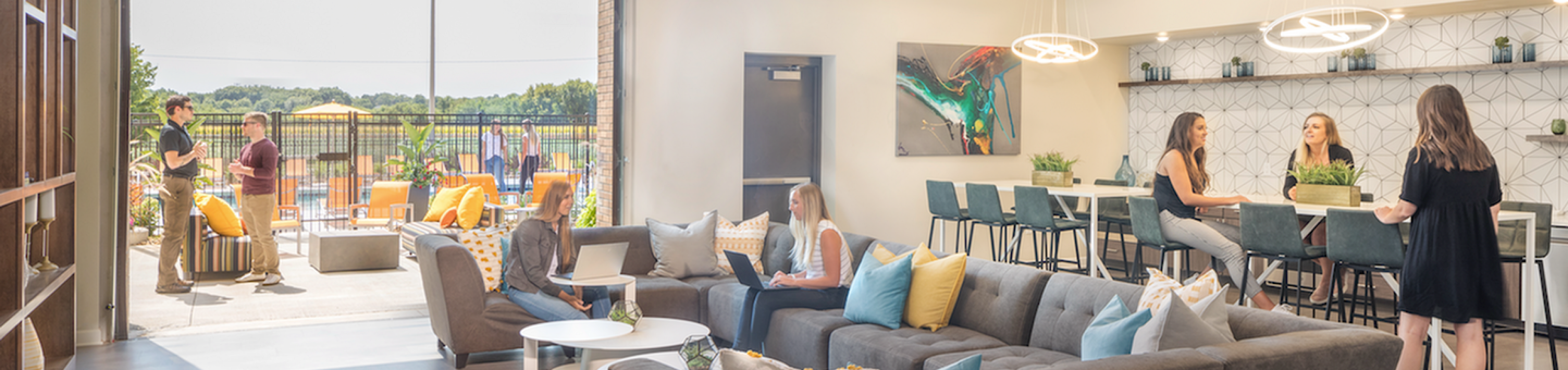 Modern open-concept lounge with plush sofas, stylish bar seating, and a vibrant outdoor patio perfect for social gatherings.