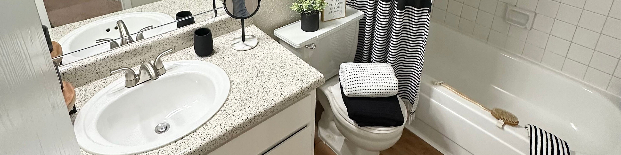 Chic bathroom featuring a modern vanity with granite countertop, elegant lighting, and a stylish black-and-white shower curtain.