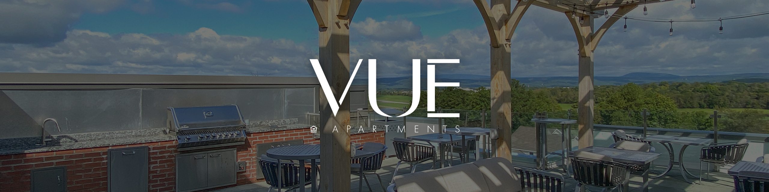 Charming rooftop terrace with modern grill, stylish seating, and scenic views at Vue Apartments.