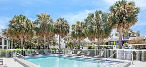 Inviting outdoor pool area surrounded by swaying palm trees and cozy lounge chairs, perfect for relaxation on a sunny day.