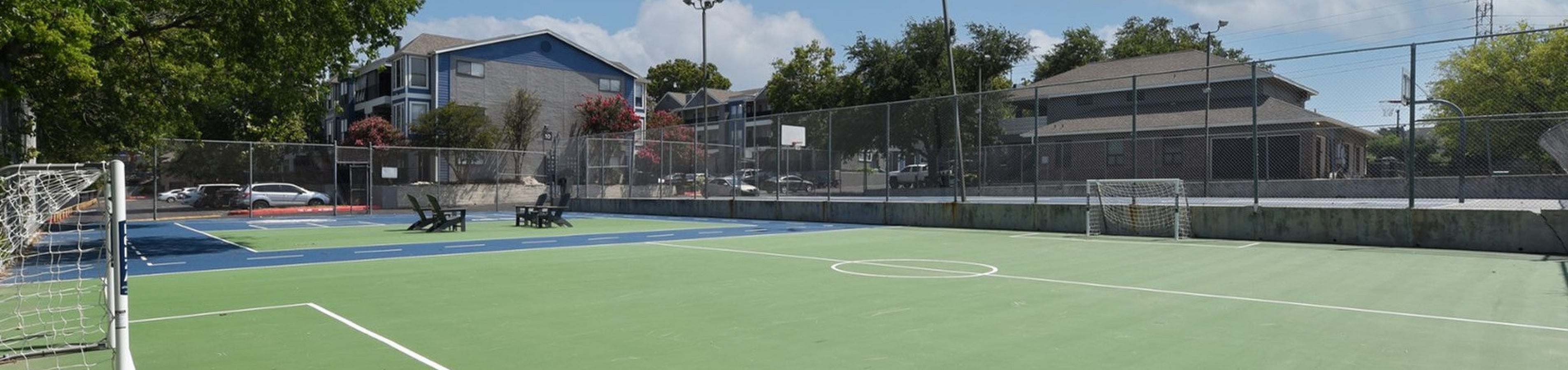 Inviting outdoor sports court with lush greenery, offering space for basketball and tennis in a serene residential neighborhood.