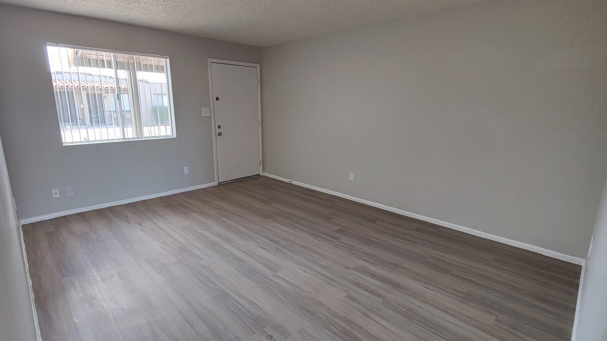 Bright living area with sleek laminate flooring and large window offering ample natural light.