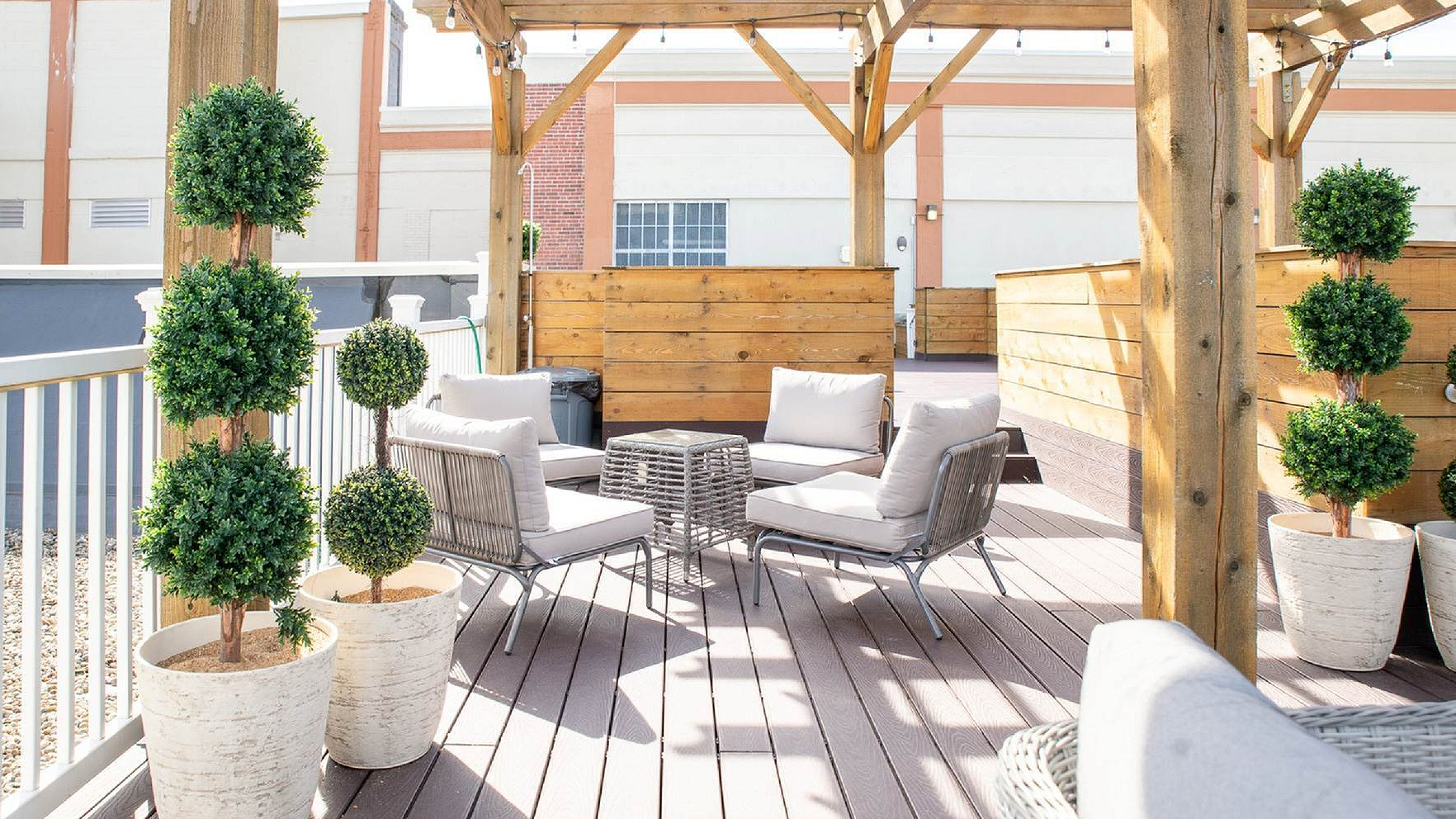 Stylish outdoor patio with cozy seating, potted plants, and a wooden pergola perfect for relaxation.