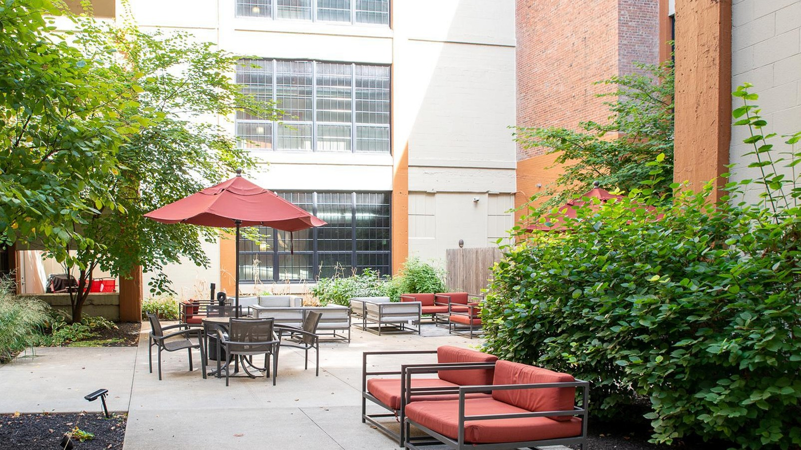 Charming outdoor patio area with lush greenery and comfortable seating, perfect for relaxation and social gatherings.
