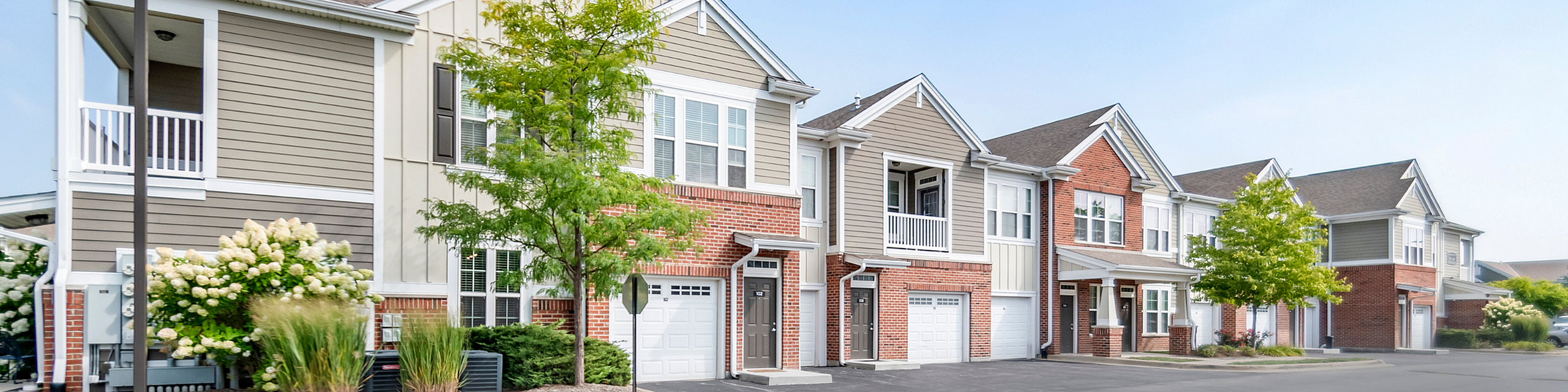 Charming townhouse exterior featuring classic brickwork, lush greenery, and inviting balconies in a serene neighborhood.