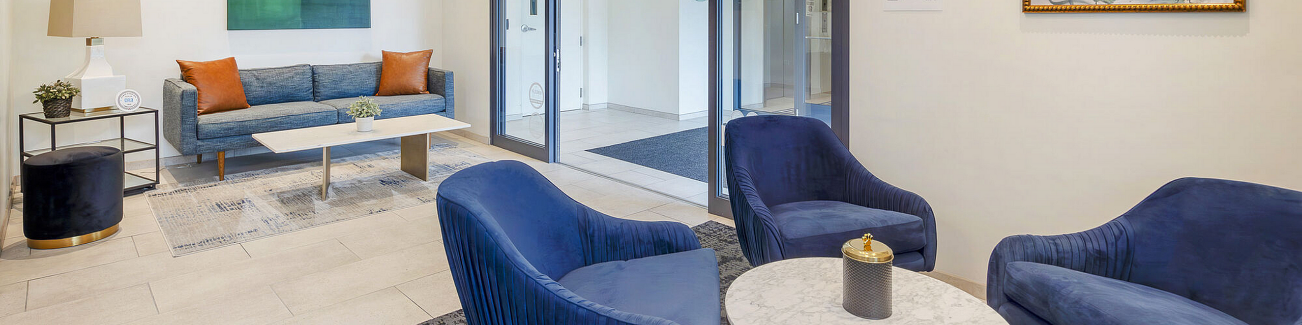 Chic apartment lounge area with modern blue velvet chairs, sleek sofa, and stylish decor, perfect for relaxation.