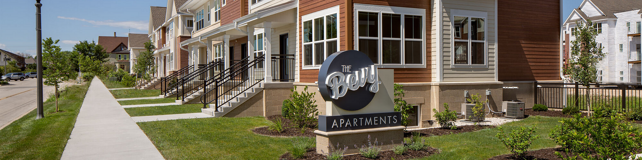 Modern apartment complex with charming architecture, lush landscaping, and inviting entrances at The Bevy Apartments.