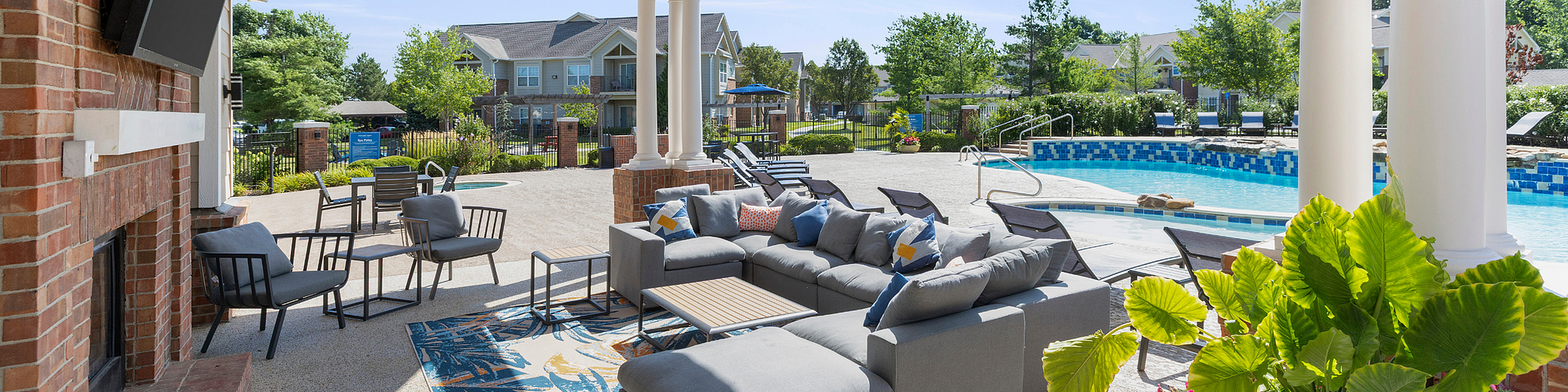 Luxurious outdoor lounge with stylish seating, vibrant greenery, and a sparkling blue pool, perfect for relaxation and entertainment.
