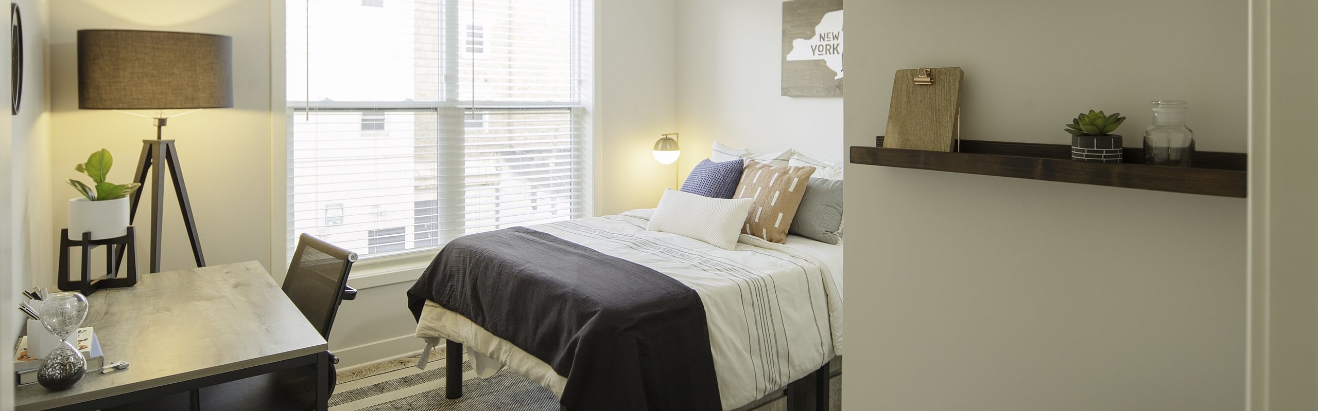 Cozy bedroom with natural light, modern desk, and stylish decor, offering a serene and inviting atmosphere.